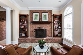 a living room with a brick fireplace and leather furniture at Brickshire Apartments, Merrillville, IN